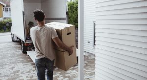 Rear view of man carrying cardboard boxes towards van