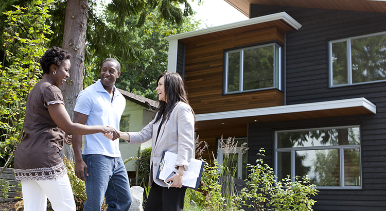 Real estate agent greeting couple at house